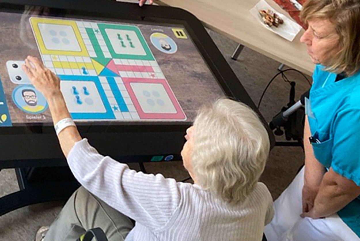 Patientin und Betreuungsassistentin testen den Aktivitätstisch CareTable Patientin und Betreuungsassistentin testen den Aktivitätstisch CareTable