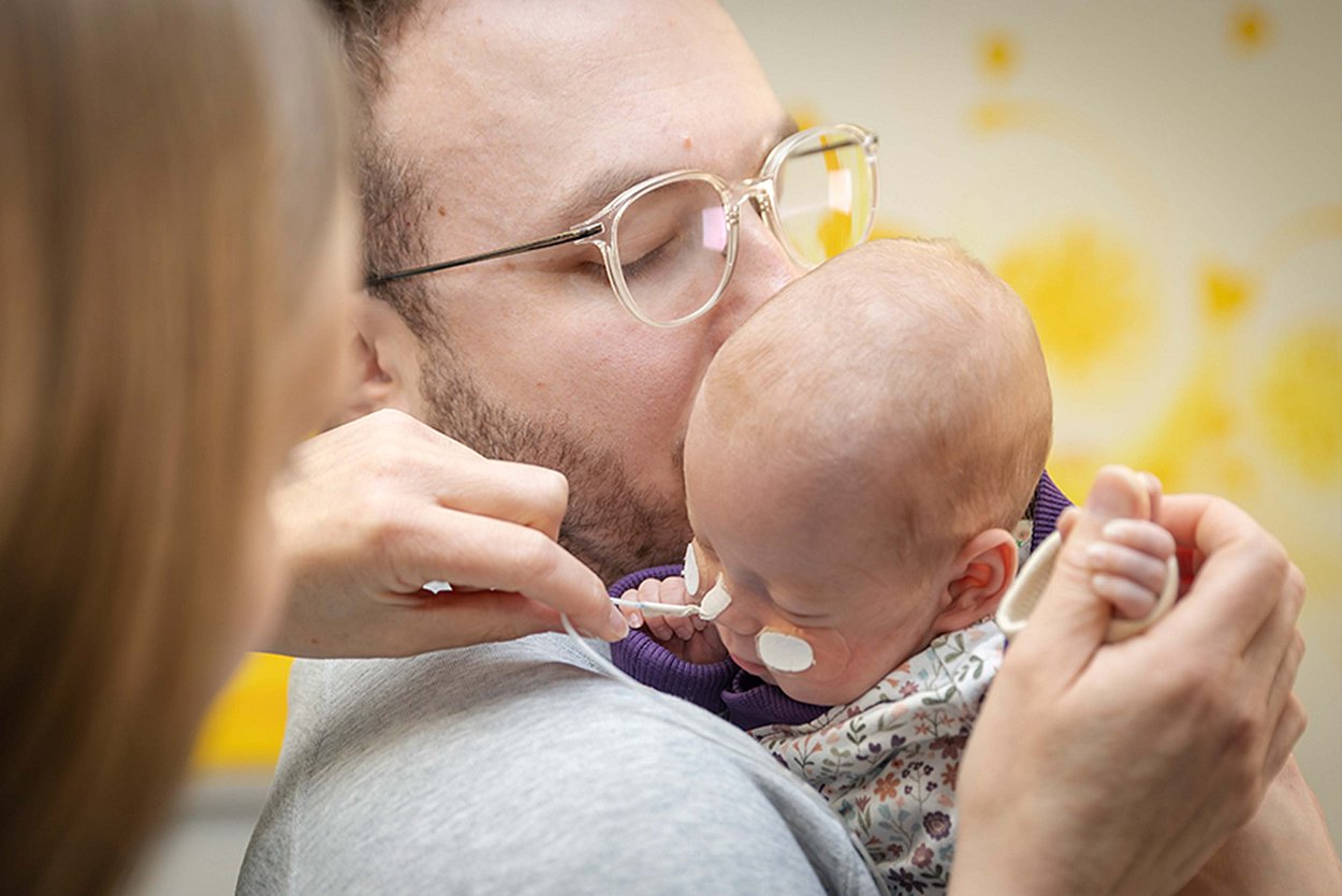 Liebevoll kümmern sich die Eltern um ihr Frühchen  mit der Sicherheit des Perinatalzentrums Rosenheim im Background.