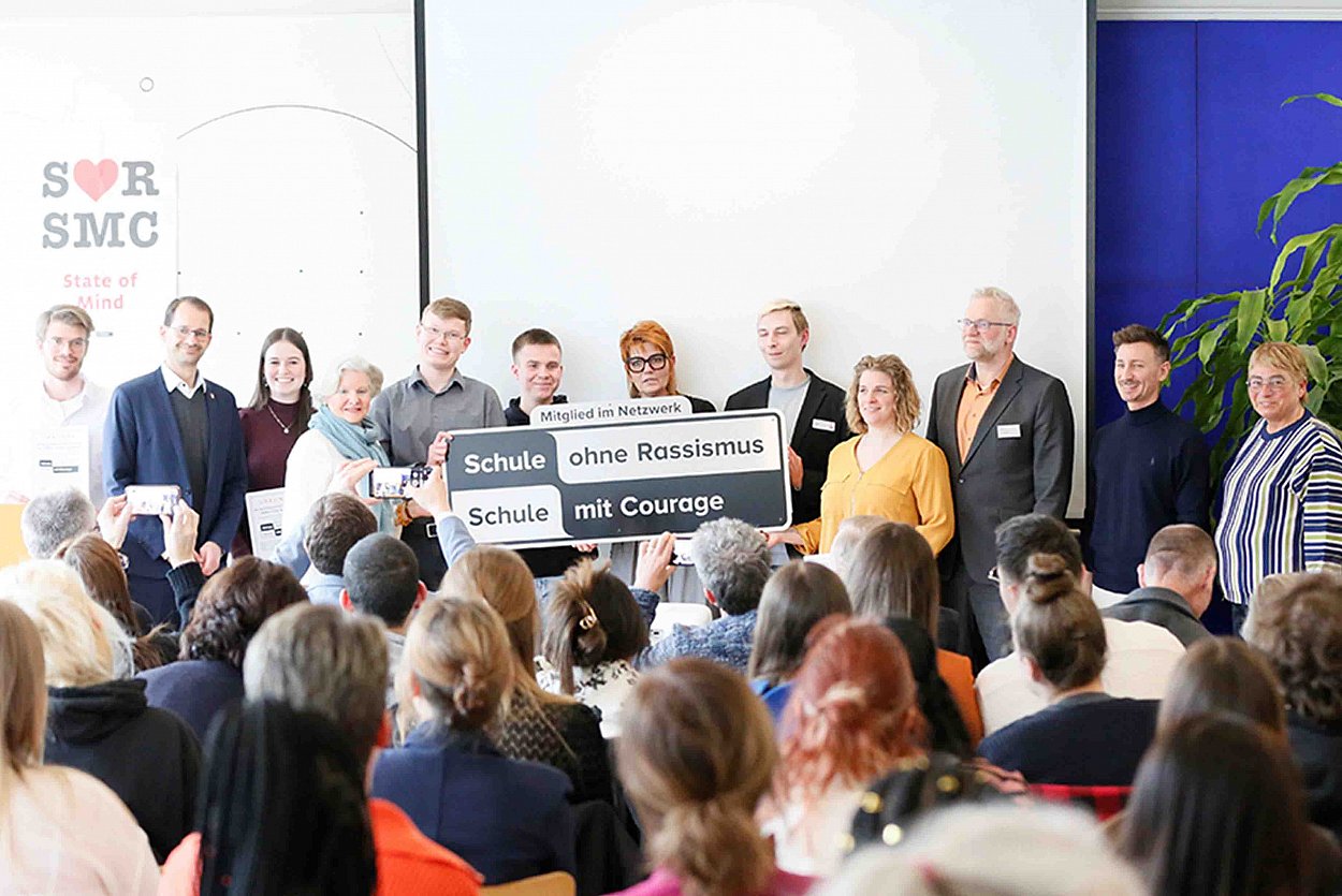 Ein Schild, das verpflichtet – Zehn Pflegeschulen der Region sind dem Netzwerk Schule ohne Rassismus – Schule mit Courage beigetreten. Neben Oberbürgermeister Andreas März (2.v.l.) freuen sich Schulpatin Sigrid Knothe (4.v.l.), die Schulsprecher, RoMed-Geschäftsführer Dr. Ulrich Schulze (3.v.r.), Regionalkoordinator Tobias Wolf (2.v.r.) sowie RoMed-Pflegedirektorin Judith Hantl-Merget (1.v.r.) Foto: bfz, Rosenheim Ein Schild, das verpflichtet – Zehn Pflegeschulen der Region sind dem Netzwerk Schule ohne Rassismus – Schule mit Courage beigetreten. Neben Oberbürgermeister Andreas März (2.v.l.) freuen sich Schulpatin Sigrid Knothe (4.v.l.), die Schulsprecher, RoMed-Geschäftsführer Dr. Ulrich Schulze (3.v.r.), Regionalkoordinator Tobias Wolf (2.v.r.) sowie RoMed-Pflegedirektorin Judith Hantl-Merget (1.v.r.) Foto: bfz, Rosenheim